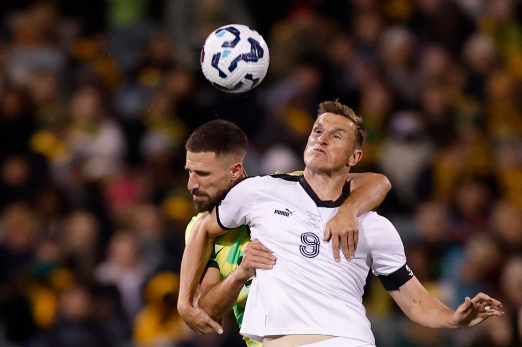 Chris Wood challenges Milos Degenek in the air during Australia vs New Zealand.